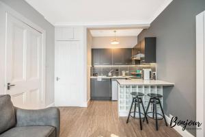 a kitchen with a couch and two bar stools at Lilas Suite Abbeyhill - 1BR-1BA 5 Mins to Meadowbank Shopping by Bonjour Residences Edinburgh in Edinburgh