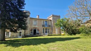 Una casa vieja con un árbol delante. en La Maison du Séguy en Saint-Ciers-de-Canesse