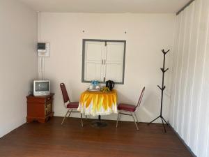a room with a table and two chairs and a television at Mango tree cafe de’ villa in Mae Pim