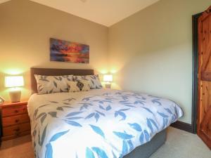 a bedroom with a bed with a blue and white comforter at Dove Cottage in Leek