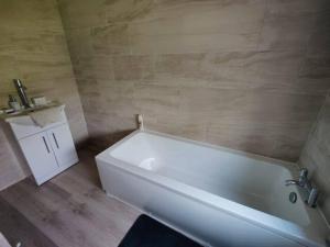 a bathroom with a white tub and a sink at Completely Renovated House with 4 Double Beds in Halton