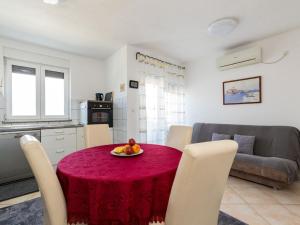 a kitchen and living room with a red table and chairs at Simplistic Apartment in Malinska near the Sea in Malinska