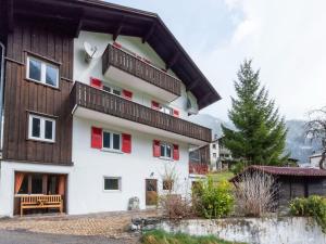 a house with red windows and a wooden roof at Holiday home in the Silvretta-Montafon ski area in Sankt Gallenkirch