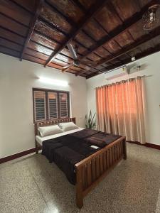 Un dormitorio con una cama grande y una ventana en Glanwoods Inn - 2BHK Antique house - Pets allowed, en Mangalore