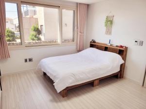 a white bedroom with a bed and a window at Stay by J in Jeju +14 photos