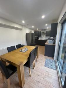 a wooden dining room table with chairs and a kitchen at 3 Bedroom House - Ideal for Contractors - Sleeps 6 in Runcorn