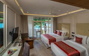 a hotel room with two beds and a television at Vythiri Village in Vythiri