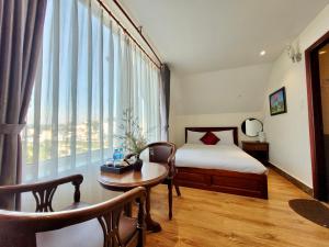 a bedroom with a bed and a table and a window at Carnival Villa in Da Lat