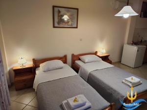 Habitación con 2 camas, 2 mesas y nevera. en Poseidon Hotel Karystos en Karystos