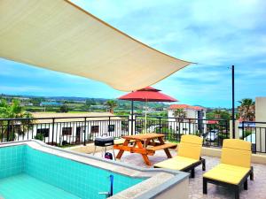 a patio with a table and chairs and an umbrella at Stay by J in Jeju