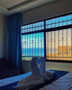 Aladnan hotel في العقبة: غرفة نوم مع منشفة على شكل قلب على سرير مع نافذة