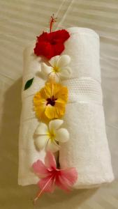 a towel with flowers on it on a bed at Va’s home in Kilifi