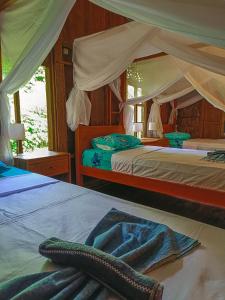 a bedroom with two beds and a canopy at Dune Alaya Ecolodge in Pemuteran