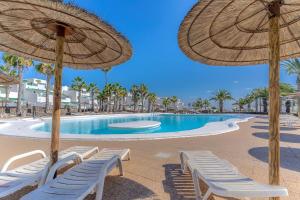 basen z leżakami i parasolami na plaży w obiekcie Bonito apartamento reformado en Las Coronas w Costa Teguise