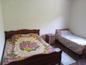 1 dormitorio con 2 camas con flores en la colcha en Bujtina Aliaj, en Tropojë