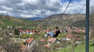 a man sitting on a swing over a village at On Top Chalet in Bran