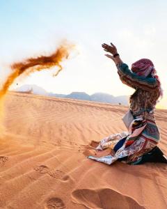 ワディ・ラムにあるHasan Zawaideh Campの砂漠の砂に腰掛けた女