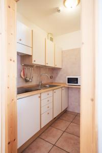 een keuken met witte kasten, een wastafel en een magnetron bij Residence Al Caminetto in Molveno