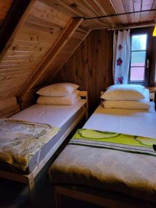 two beds in a wooden cabin with a window at Domek wypoczynkowy Gowidlino in Gowidlino