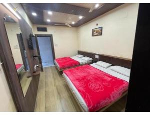 Hotel Radhika Palace, Mount Abu, Rajasthan في مونت ابو: غرفة بسريرين عليها اغطيه حمراء