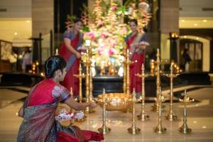 une femme debout devant un autel avec des bougies dans l'établissement Taj Lands End, à Mumbai