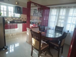 a kitchen with a dining room table and chairs at SMS HOME STAy in Kushālnagar