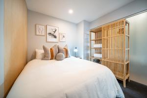 een slaapkamer met een groot wit bed en een boekenplank bij Paradiso on Bent Adelaide in Adelaide