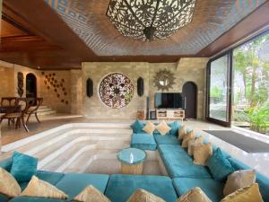 a living room with a blue couch and a chandelier at Akasha New Earth Haven Villa in Ubud