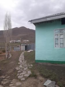 a blue house with a stone path next to a building at Xinaliq BedBreakfast in Quba