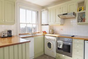 a kitchen with white cabinets and a washer and dryer at High View, Southwold High Street (2 bed, 2 bath, allocated parking, balcony) in Southwold