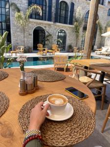 a person sitting at a table with a cup of coffee at Rhea Alaçatı Boutique Hotel in Alacati