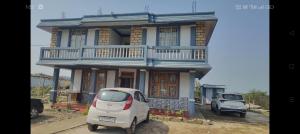 een kleine witte auto geparkeerd voor een huis bij Breeze Hills Inn in Cherrapunji