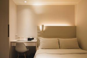a bedroom with a bed with a desk and a chair at SWIIO Hotel Ximending in Taipei