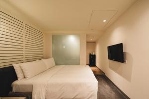 a bedroom with a white bed and a flat screen tv at SWIIO Hotel Ximending in Taipei