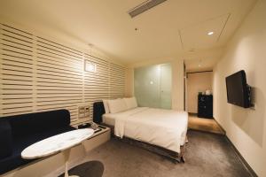 um quarto com uma cama, um sofá e uma televisão em SWIIO Hotel Ximending em Taipei