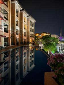 ein Gebäude mit einer Spiegelung im Wasser in der Nacht in der Unterkunft Luxury on Melaka River in Malakka