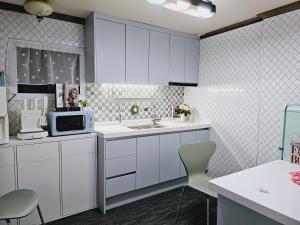 a kitchen with white cabinets and a microwave at K Highstel Uijeongbu 35 in Uijeongbu