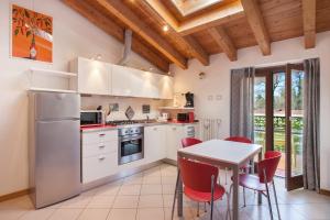una cucina con elettrodomestici bianchi e un tavolo con sedie rosse di Apartment Ponte Tesina a Costermano