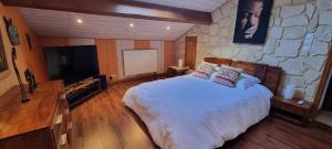 a bedroom with a large bed and a stone wall at La Forge du Rosay in Viry