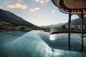 a swimming pool with mountains in the background at Alpina Alpendorf in Sankt Johann im Pongau
