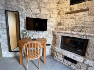 a stone fireplace with a wooden table and a chair at Rhea Alaçatı Boutique Hotel in Alaçatı