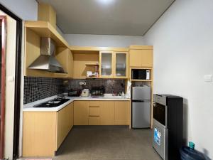 a small kitchen with yellow cabinets and a refrigerator at Villa Ophelia at Vimala Hills in Bogor