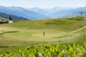 a person standing on a golf course on a hill at Hôtel Alpen Lodge in La Rosière