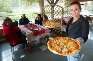 Kobieta trzymająca dwie duże pizze w restauracji. w obiekcie GOSTILNA IN PIZZERIA KOVAČ w mieście Litija