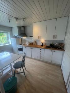 a kitchen with white cabinets and a table with a chair at Cosy apartment with free parking in Bergen