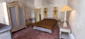 a bedroom with a bed and a table and a lamp at Logis La Vachère in Avallon