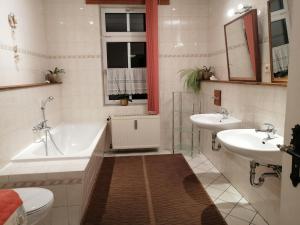 ein Badezimmer mit zwei Waschbecken, einer Badewanne und einem WC in der Unterkunft Ferienwohnung HARZgeNUSS in Wernigerode