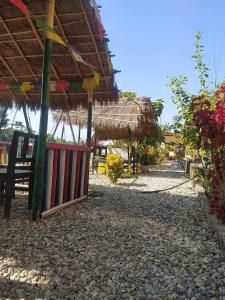 a building with a straw roof on a beach at Busy Bee Guest House in Sauraha