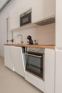 a white kitchen with a stove and a microwave at Apartamento Barcelona centro in Barcelona
