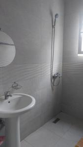 uma casa de banho branca com um lavatório e um chuveiro em Vila Hyseni em Durrës